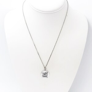 May include: Silver necklace with a round pendant that says "United We Stand" in a cursive font.