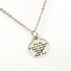 May include: A silver necklace with a round pendant that reads "For by grace you have been saved through faith. Eph. 2:8"