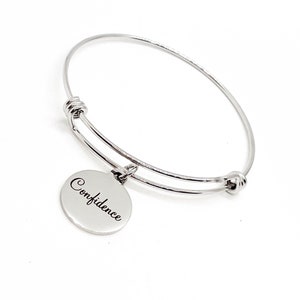 May include: Silver bangle bracelet with a round charm that says "Confidence".