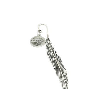 May include: A silver-colored bookmark in the shape of a feather. A small, round charm is attached to the top with the word "Lacrosse" and other text. The bookmark is on a white background.