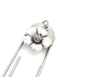 Op de afbeelding: Zilveren bladwijzer met een bloembedel. De bloem heeft een wit metalen lichaam en een gele kern.