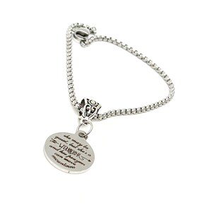 May include: A silver-toned bracelet with a round pendant. The pendant has the inscription "she may be quiet, but she's a WARRIOR and her prayers can move mountains". The bracelet features a decorative bead and a chain-link style band.