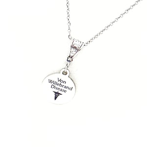 May include: Silver necklace with a round pendant that says "Von Willebrand Disease" with a caduceus symbol.