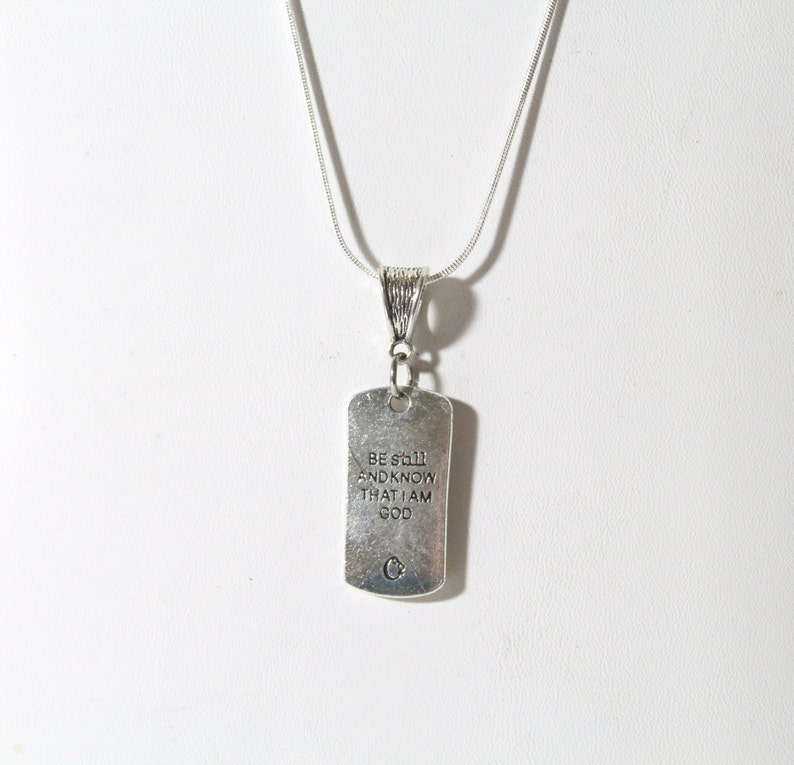 May include: Silver necklace with a silver tag pendant that reads "Be still and know that I am God".
