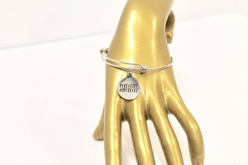Peut inclure: Bracelet en argent avec un charme rond qui dit "Perfectly Imperfect".