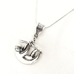 May include: A silver necklace with a sloth pendant. The sloth is hanging from a branch and has a detailed design.