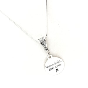 May include: Silver necklace with a round pendant that says "When words fail... Music speaks" with a musical note symbol.