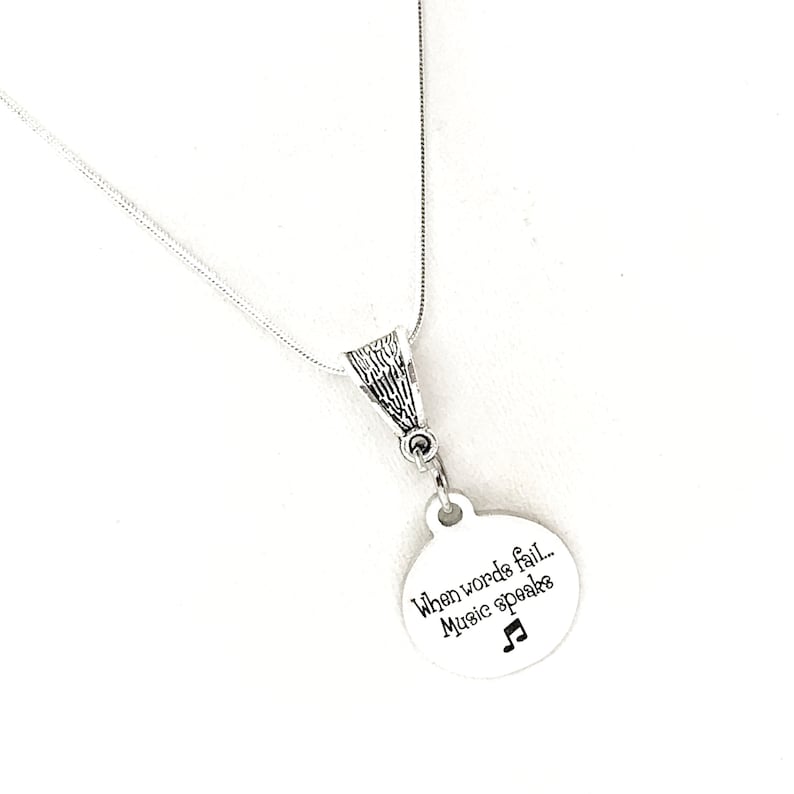 May include: Silver necklace with a round pendant that says "When words fail... Music speaks" with a musical note symbol.
