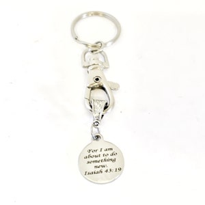 May include: Silver keychain with a silver clip and a round charm with the text "For I am about to do something new, Isaiah 43:19".