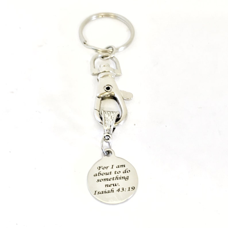 May include: Silver keychain with a silver clip and a round charm with the text "For I am about to do something new, Isaiah 43:19".