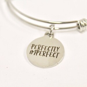 Peut inclure: Bracelet en argent avec un charme qui dit "Parfaitement imparfait".
