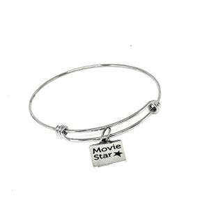 May include: A silver-colored, adjustable bangle bracelet with a rectangular charm. The charm is engraved with the words "Movie Star" and a star symbol. The bracelet is designed to be worn on the wrist.