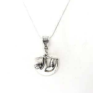 May include: Silver necklace with a sloth pendant. The sloth is hanging upside down from a branch.