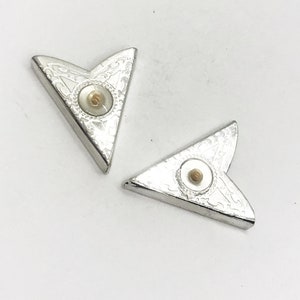 May include: Two silver corner protectors with a decorative design and a white pearl-like center.