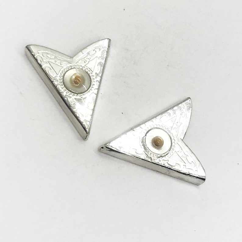 May include: Two silver corner protectors with a decorative design and a white pearl-like center.