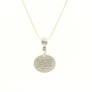 Op de afbeelding: Zilveren ketting met een ronde hanger met de inscriptie "Hij die in u een goed werk begonnen is, die zal het voltooien. Fil. 1:6"