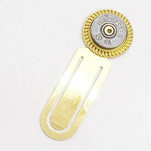 May include: Gold bookmark with a 20 GA Winchester shotgun shell attached to the top. The shell is silver with black lettering.