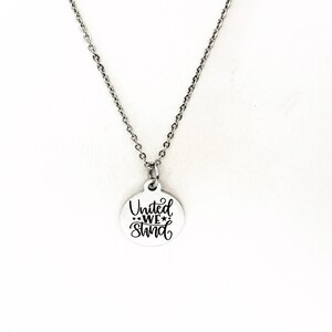 May include: A silver necklace with a round pendant that says "United We Stand" in black lettering.