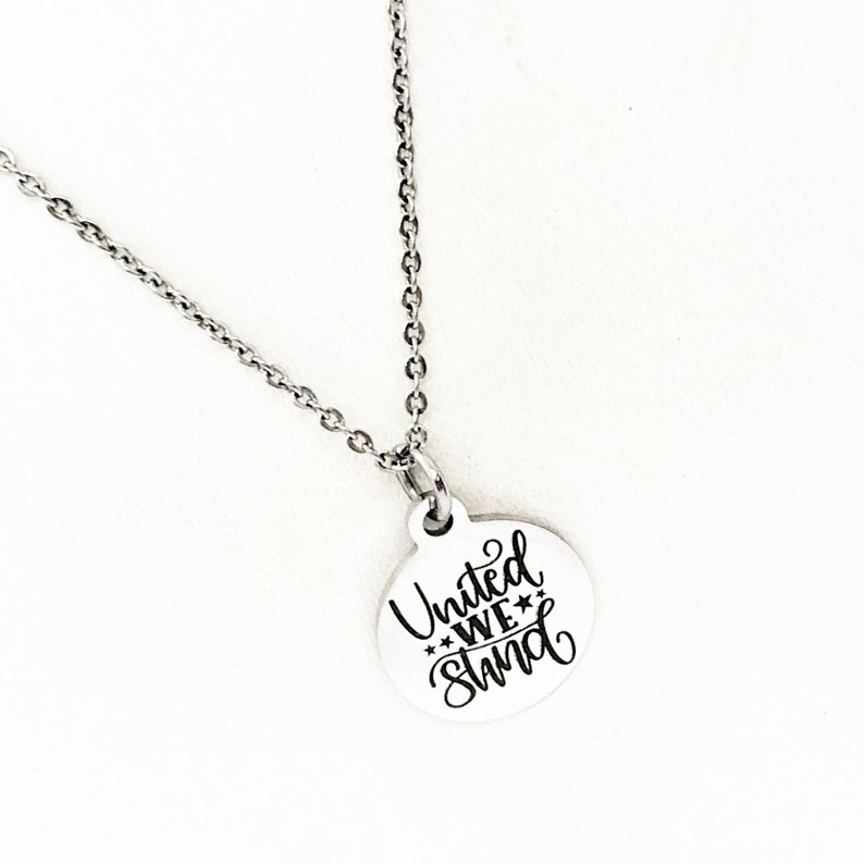 May include: A silver necklace with a round pendant that says "United We Stand" in black lettering.