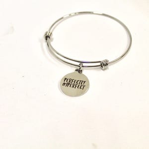 Peut inclure: Bracelet en argent avec un charme qui dit "Parfaitement imparfait".