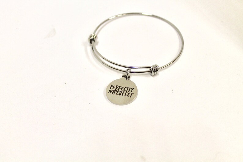 Peut inclure: Bracelet en argent avec un charme qui dit "Parfaitement imparfait".