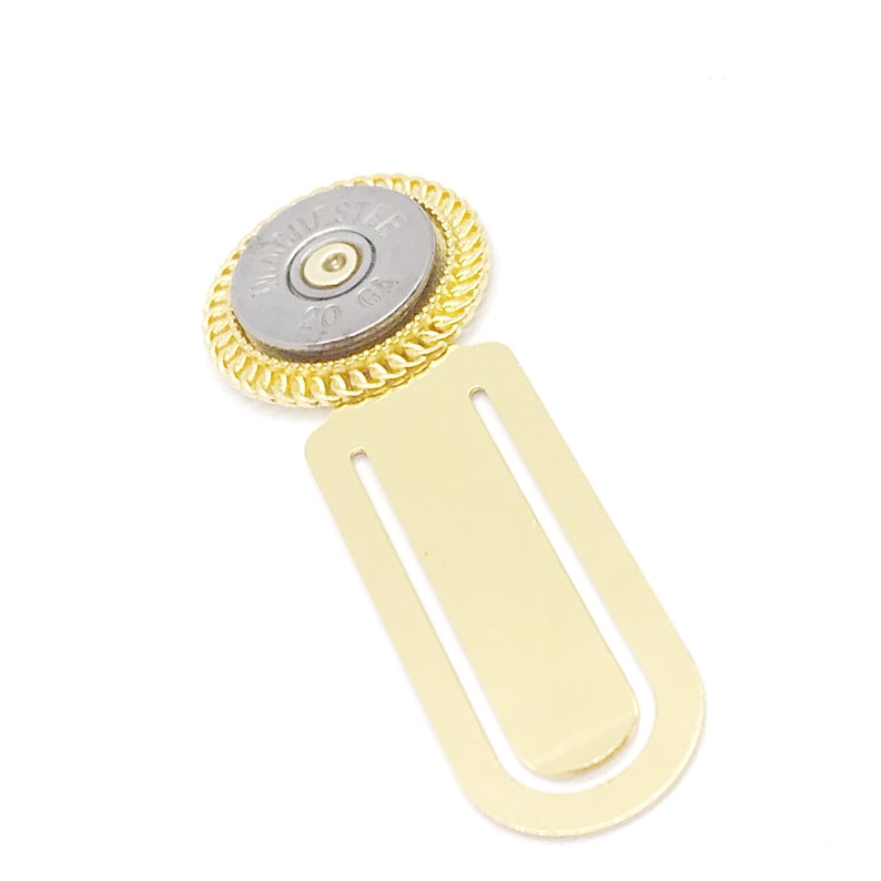 May include: Gold bookmark with a 20 GA shotgun shell in the center. The shell is silver with black lettering that reads "WINCHESTER 20 GA".