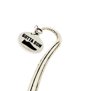 Può includere: Segnalibro d'argento con un ciondolo rotondo che dice "Gotta Run" con un'icona di scarpa da corsa.