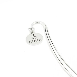 May include: Silver bookmark with a round charm that says "I ♥ 01000001 01010011 00100011".
