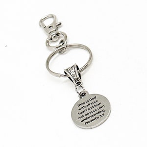 May include: Silver keychain with a round charm that reads "Trust in God with all your heart and lean not on your own understanding. Proverbs 3:5".
