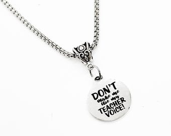 May include: Silver necklace with a round pendant that says "Don't make me use my teacher voice!"