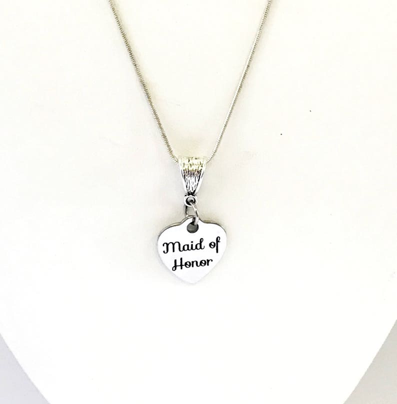 Puede incluir: Collar de plata con un colgante en forma de coraz&oacute;n que dice "Maid of Honor".