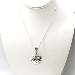May include: A silver necklace with a sloth pendant. The sloth is hanging upside down from a branch.