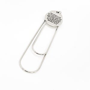 May include: A silver-colored metal bookmark with a circular top and a large paperclip-style design. The circular top has the text "And whoever will not receive you nor hear your words...Matthew 10:14" in black lettering.