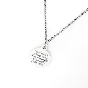 May include: A silver necklace with a round pendant that reads "Your word is a lamp to my feet and a light to my path. Psalm 119:105"