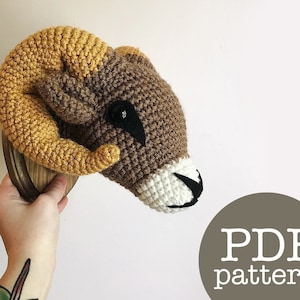 May include: Crochet pattern for a brown and yellow ram's head with white and black eyes. The pattern is available as a PDF download.