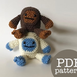 May include: A crocheted brown yeti with a white and blue face sitting on top of a crocheted white yeti with a blue face. The text "PDF pattern" is written in white on a brown circle.