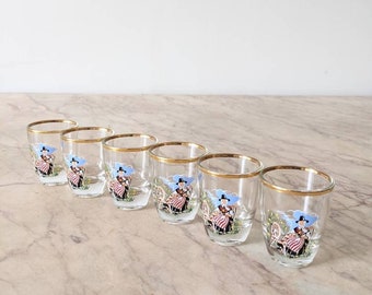 A set of six kitsch vintage shot glasses depicting Welsh ladies in traditional dress, six 1950s gilt banded shot glasses