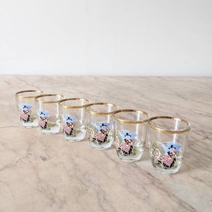A set of six kitsch vintage shot glasses depicting Welsh ladies in traditional dress, six 1950s gilt banded shot glasses