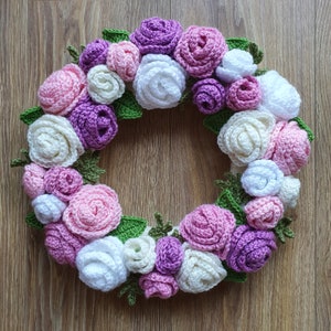 Pu&ograve; includere: Una ghirlanda all'uncinetto con fiori rosa, bianchi e viola. La ghirlanda &egrave; realizzata in filato e ha un design a foglie verdi.