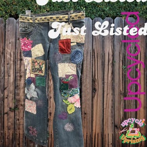 Puede incluir: Vaqueros de mezclilla reciclados con parches de tela coloridos y adornos florales. Los vaqueros tienen un cinturón decorativo y cuelgan de una valla de madera. El texto "Just Listed" es visible.