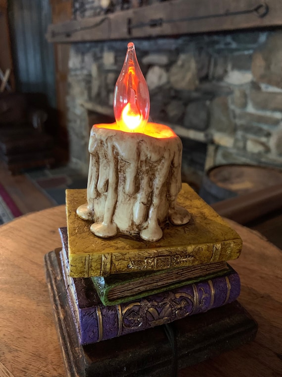 Wunderliche antike Bücher-Lampe oder Nachtlicht mit tropfender Kerze und flackernder Glühbirne
