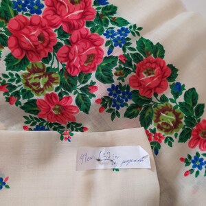 Pode incluir: Um tecido branco com um padr&atilde;o floral de rosas vermelhas e flores azuis. O tecido tem 91 cm (32 polegadas) de largura.