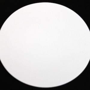 May include: A plain white, circular object against a black background. The object is a solid, opaque white, and the edges are smooth and rounded. The contrast between the white circle and the black background is stark.