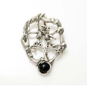Puede incluir: Un colgante de plata con dos esqueletos entrelazados dentro de un diseño de árbol. El colgante tiene una piedra preciosa negra en la parte inferior.