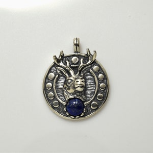 May include: Silver pendant featuring a detailed deer head with antlers, set against a circular background with a blue lapis lazuli stone in the center.