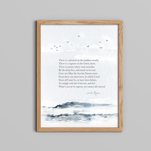 Op de afbeelding: Een ingelijst afdruk met een aquarel van een zeelandschap met een citaat van Lord Byron. Het citaat luidt: "Er is een plezier in de padloze bossen, Er is een extase aan de eenzame kust, Er is een samenleving waar niemand binnendringt Aan de diepe zee, en muziek in zijn gebrul: Ik hou niet minder van de mens, maar van de natuur meer. Van deze onze ontmoetingen, waarin ik steel Van alles wat ik kan zijn, of ben geweest, Om me te mengen met het universum, en te voelen Wat ik nooit kan uitdrukken, maar niet alles kan verbergen."