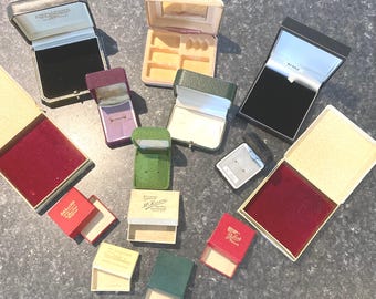 May include: A collection of 11 empty jewelry boxes in various colors and sizes. The boxes are made of cardboard and have velvet interiors. Some of the boxes have labels with the names of jewelry stores.