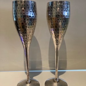 Par höga vinbägare i hamrad silverfärgad metall. Dekorativa vinbägare.