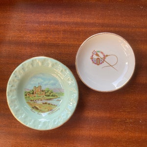May include: Two decorative ceramic plates. One is light green with a gold rim and a landscape painting of a castle and the text "Ross Castle Killarney". The other is white with a gold rim and a colorful emblem.