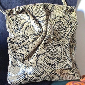 May include: A brown and black snakeskin-patterned handbag with a single strap.